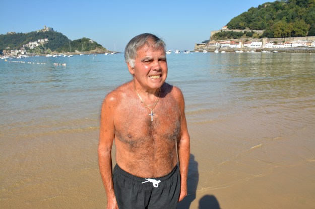 hombre con cruz y pecho perlado en la playa